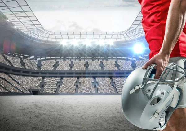 Игрок в американский футбол, стоя с шлем против цифровой составной стадион — стоковое фото