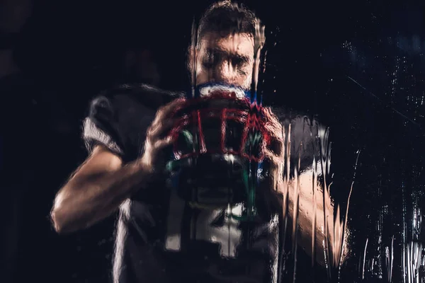 View American Football Player Holding Helmet Black Wet Glass — стоковое фото